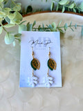 Handmade polymer clay dangle earrings with white RicRac leaf design, gold filigree leaf, and green metal accent – displayed on Mandi P Designs card