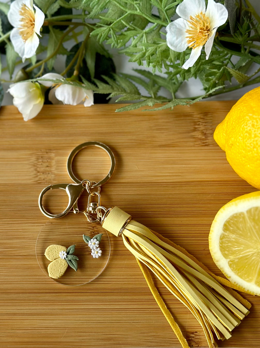 Keychain with tassel on a wooden board with lemons and flowers