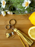 Keychain with tassel on a wooden board with lemons and flowers