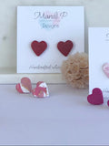 Heart-shaped earrings with pink and white marble design on a white surface.